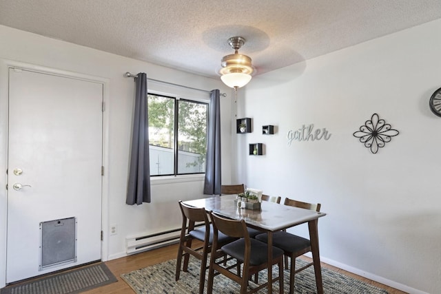 dining space featuring ceiling fan, dark hardwood / wood-style floors, a textured ceiling, and baseboard heating