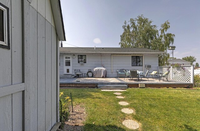 rear view of house with a wooden deck and a lawn