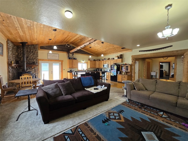 living room featuring lofted ceiling, a chandelier, wooden ceiling, a wood stove, and light wood-type flooring