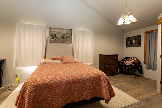 bedroom featuring a notable chandelier, lofted ceiling, and wood-type flooring