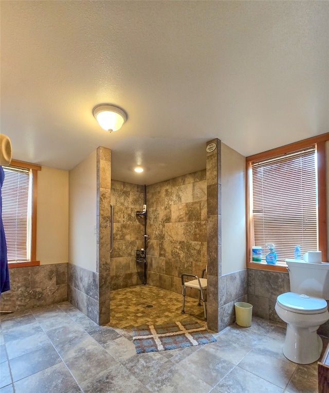 bathroom featuring a tile shower, tile patterned floors, and toilet