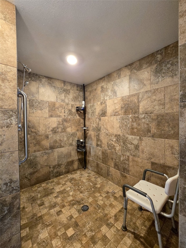 bathroom with a tile shower and a textured ceiling