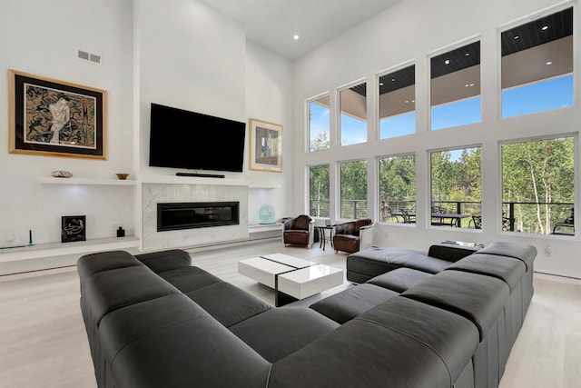 living room featuring a fireplace, light hardwood / wood-style flooring, and a high ceiling