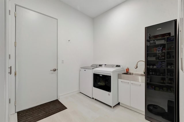 washroom featuring cabinets, separate washer and dryer, sink, and light wood-type flooring