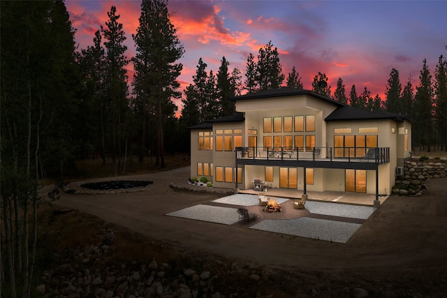 back house at dusk with a fire pit and a patio