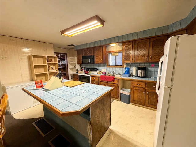 kitchen with sink, tasteful backsplash, electric range oven, tile counters, and white fridge