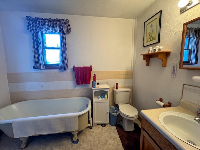 bathroom with vanity, toilet, a bathing tub, and tile walls