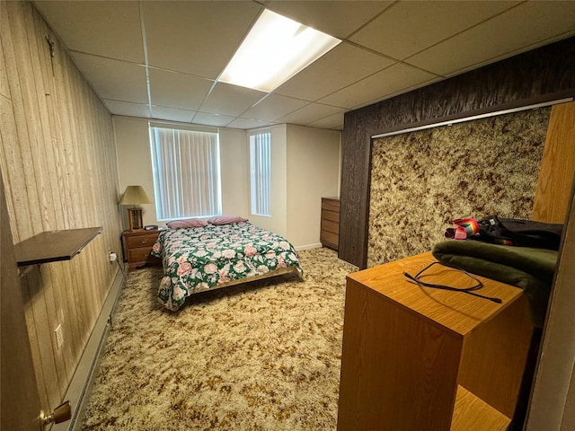 carpeted bedroom with wood walls and a drop ceiling