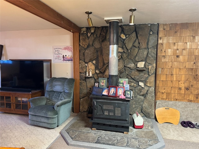 living room featuring beamed ceiling and a wood stove