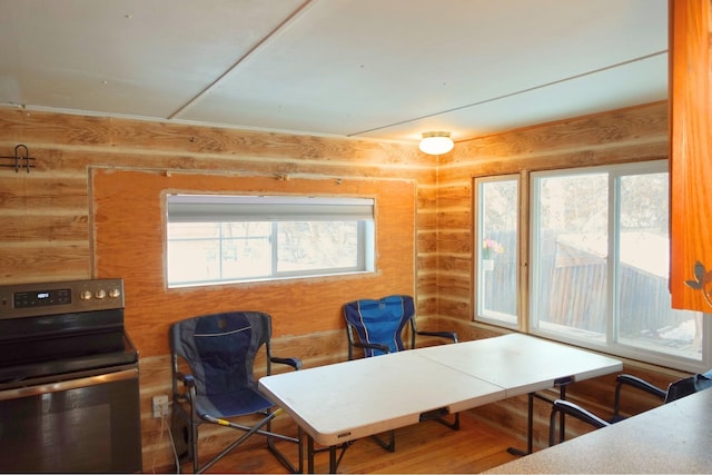 interior space with wood walls, wood-type flooring, plenty of natural light, and electric stove