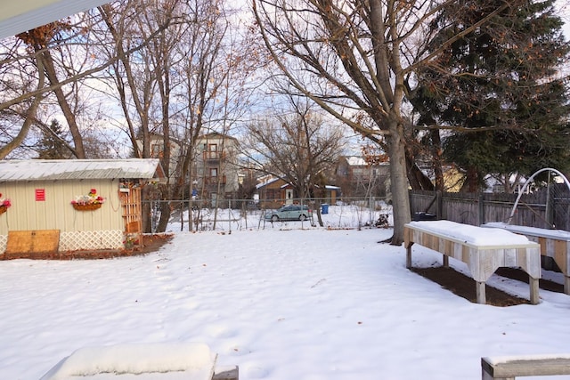 yard layered in snow featuring a storage shed