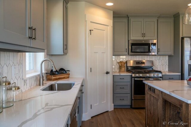 kitchen featuring tasteful backsplash, stainless steel appliances, sink, light stone countertops, and dark hardwood / wood-style floors