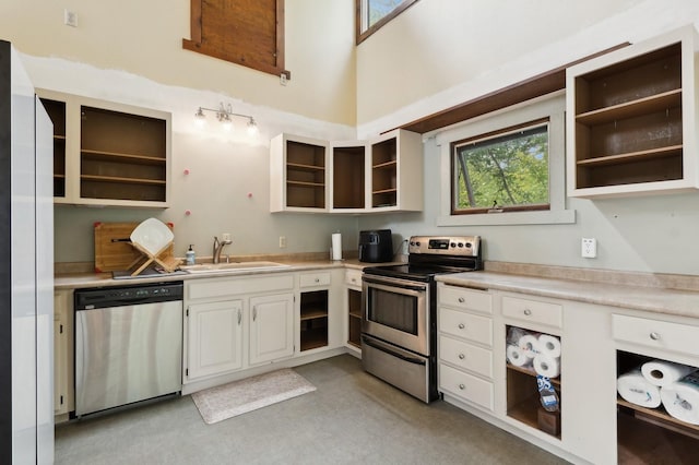 kitchen with light countertops, a sink, open shelves, and stainless steel appliances