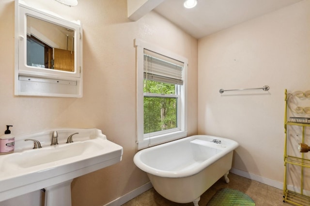 full bathroom featuring a freestanding tub, a sink, and baseboards