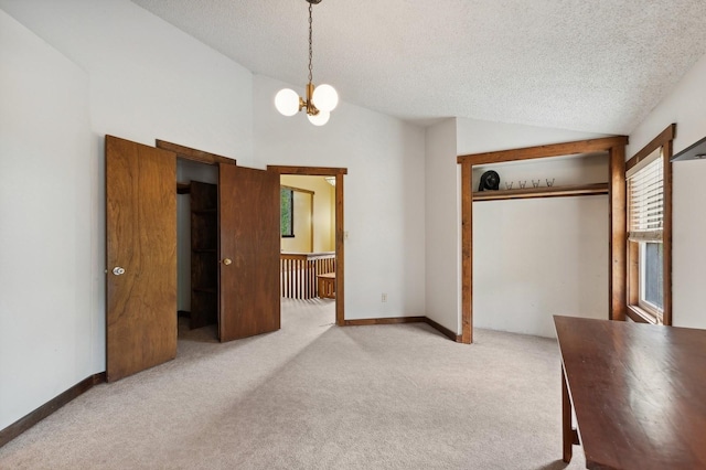 unfurnished bedroom with a textured ceiling, carpet flooring, a notable chandelier, and lofted ceiling