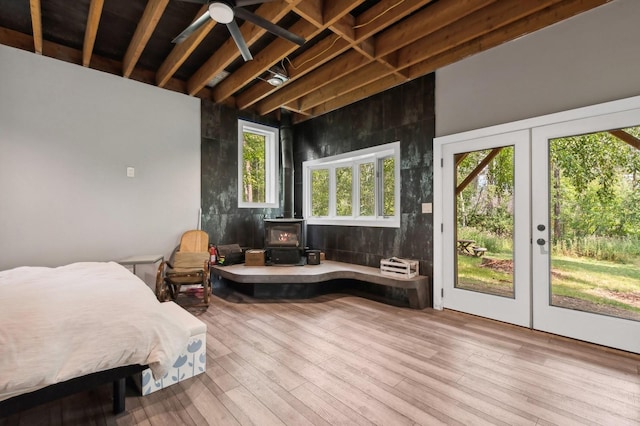 bedroom with a wood stove, french doors, access to exterior, and wood finished floors