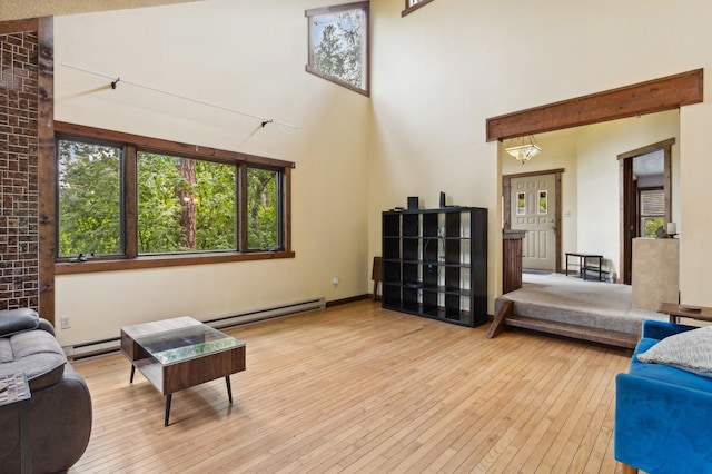 living room with a high ceiling, a baseboard heating unit, and hardwood / wood-style flooring