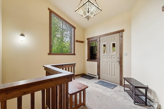 foyer featuring baseboard heating, a chandelier, baseboards, and a wealth of natural light