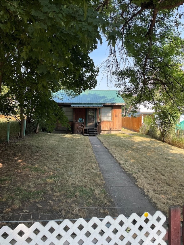 exterior space with entry steps, metal roof, a front yard, and fence