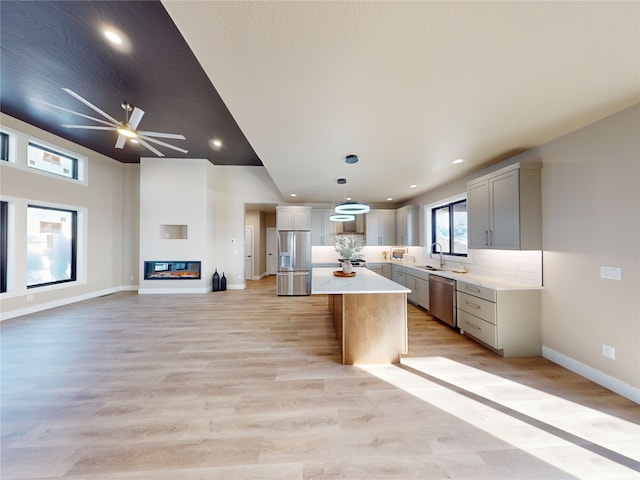 kitchen featuring appliances with stainless steel finishes, decorative light fixtures, sink, gray cabinetry, and a center island