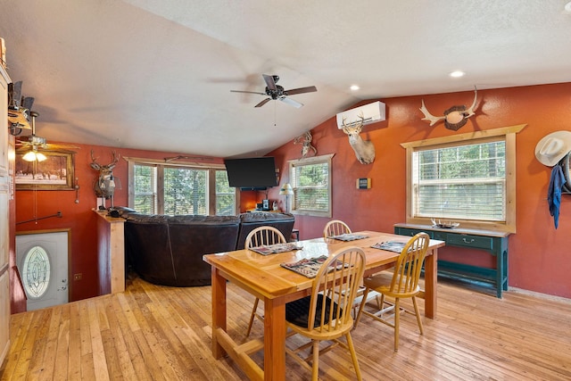 635 Lore Lake Rd, Kalispell, MT 59901 - dining area with a wall unit AC, light wood-style floors, vaulted ceiling, a textured ceiling, and ceiling fan