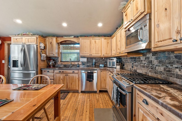 635 Lore Lake Rd, Kalispell, MT 59901 - kitchen with stainless steel appliances, a sink, backsplash, light brown cabinetry, and light wood finished floors