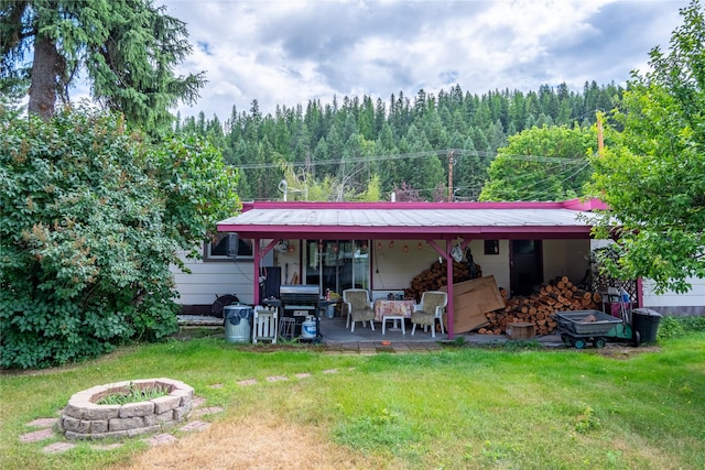 822 W Balsam St, Libby, MT 59923 - rear view of property with a fire pit, a forest view, a yard, and a patio