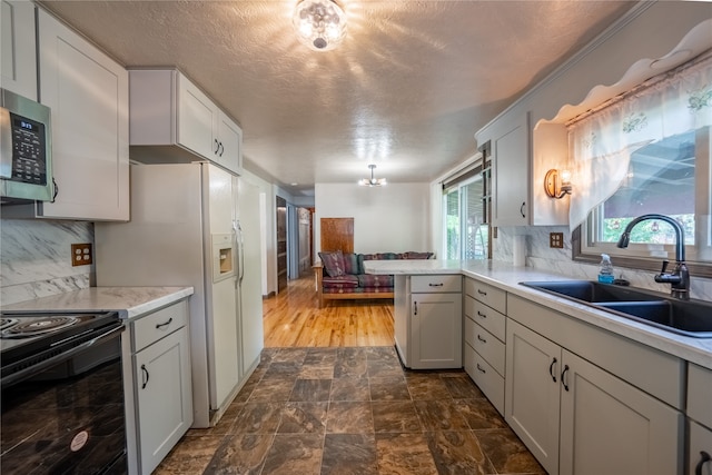 kitchen with kitchen peninsula, sink, a textured ceiling, black / electric stove, and decorative backsplash