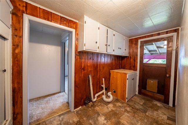 laundry area featuring dark carpet and wooden walls