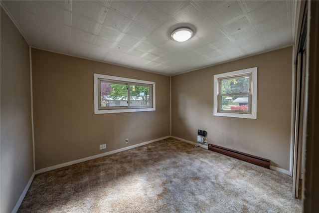 spare room featuring a baseboard heating unit, carpet floors, and plenty of natural light