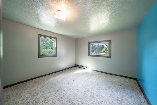 carpeted empty room with a textured ceiling and a baseboard heating unit