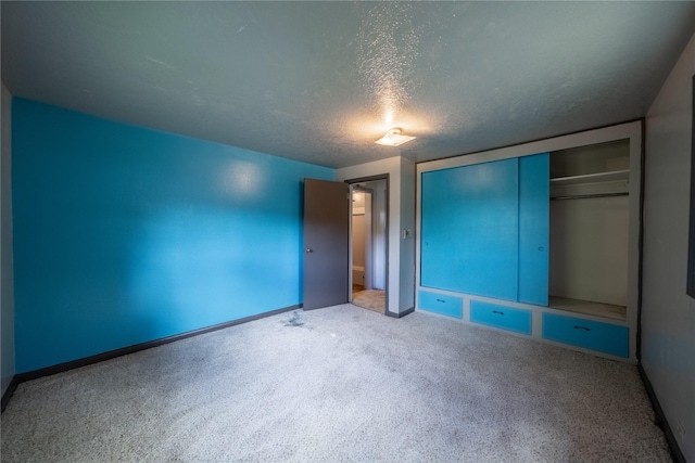 unfurnished bedroom featuring a textured ceiling, baseboards, carpet, and a closet