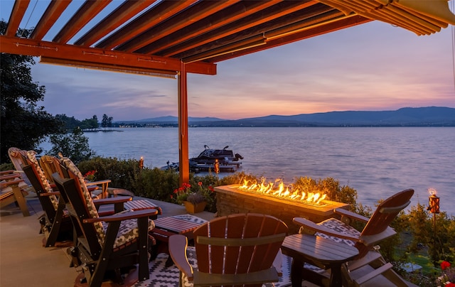 patio terrace at dusk with a fire pit and a water and mountain view