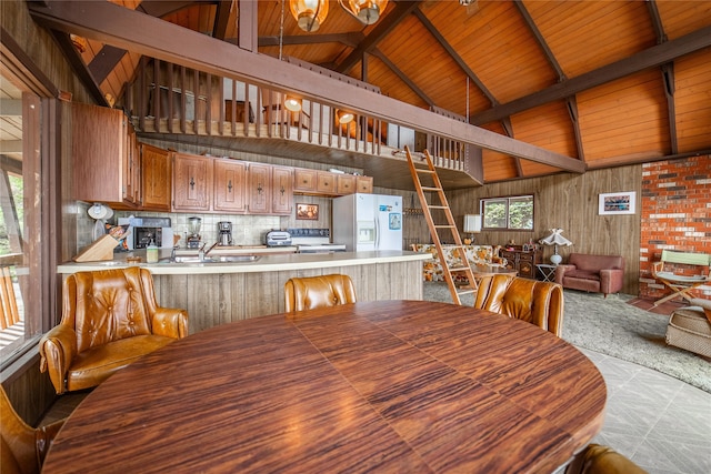 dining space featuring beam ceiling, wood ceiling, sink, and high vaulted ceiling