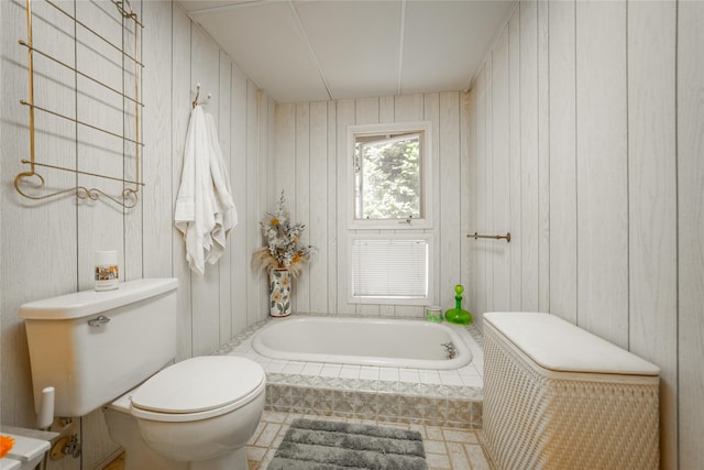 bathroom featuring wood walls, toilet, tile patterned floors, and tiled bath