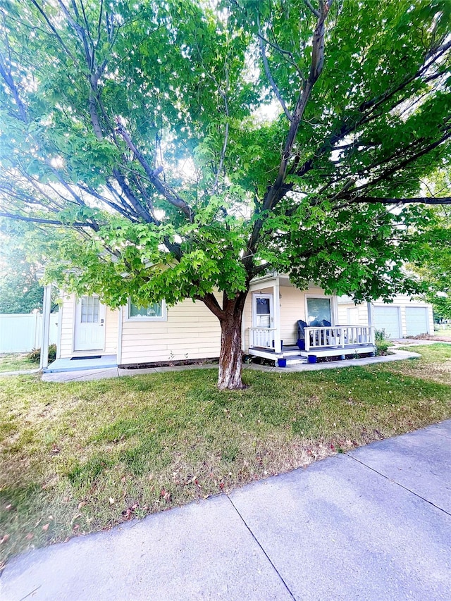 view of front of property featuring a garage, a porch, and a front lawn