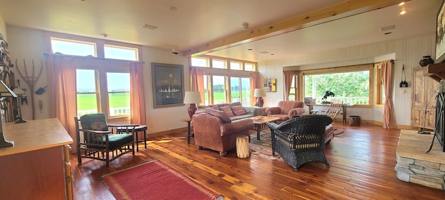 living room with a wealth of natural light, hardwood / wood-style floors, and beam ceiling