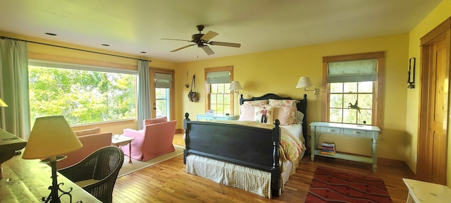 bedroom featuring ceiling fan, wood-type flooring, and multiple windows