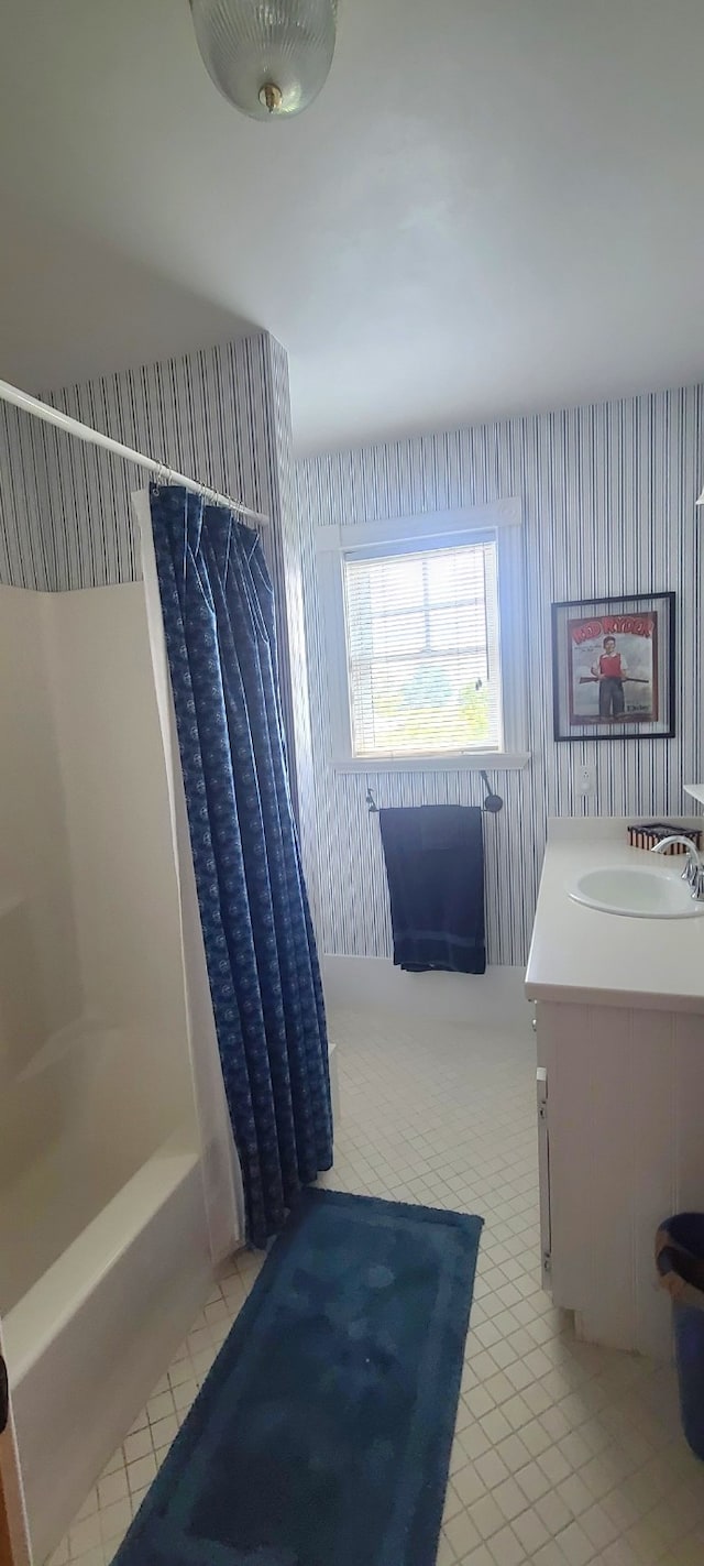 bathroom with tile patterned flooring, shower / bathtub combination with curtain, and vanity