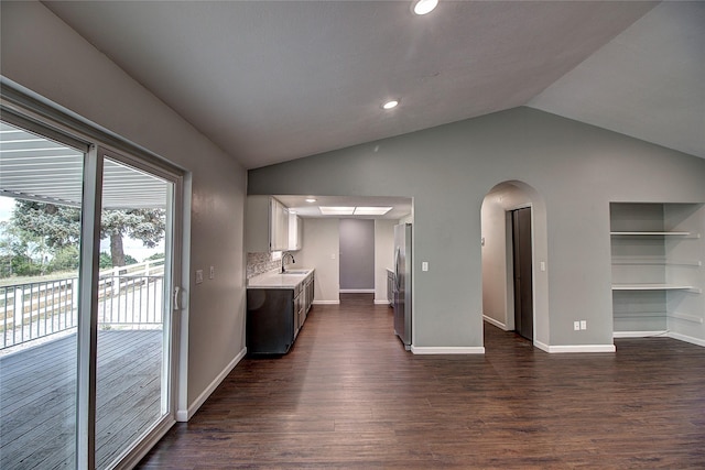 kitchen featuring dark wood finished floors, vaulted ceiling, light countertops, and a sink