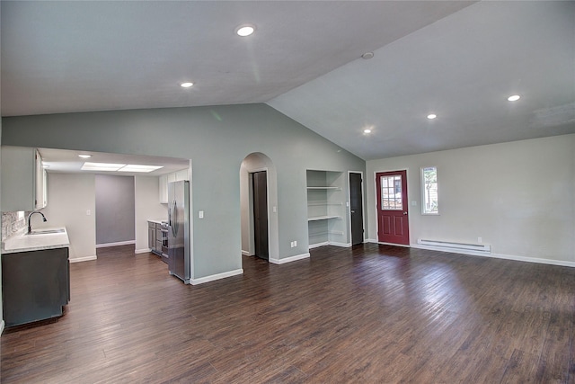 unfurnished living room featuring arched walkways, dark wood-style flooring, baseboard heating, vaulted ceiling, and a sink