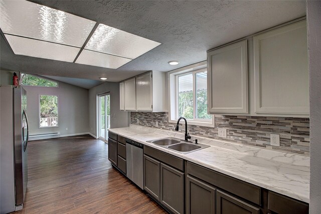 kitchen featuring lofted ceiling, a sink, light countertops, appliances with stainless steel finishes, and dark wood finished floors