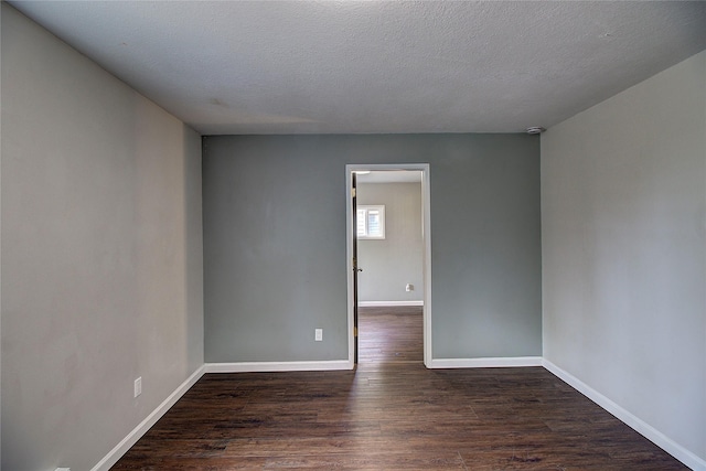 spare room with dark wood finished floors, a textured ceiling, and baseboards