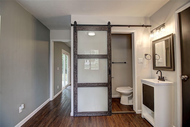 bathroom featuring vanity, wood finished floors, toilet, and baseboards