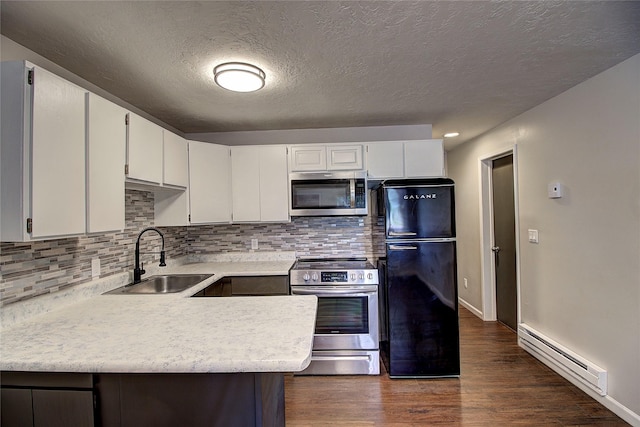 kitchen with stainless steel appliances, dark wood-type flooring, a sink, light countertops, and baseboard heating