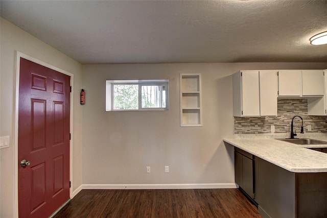 kitchen with dark wood finished floors, light countertops, decorative backsplash, white cabinets, and a sink