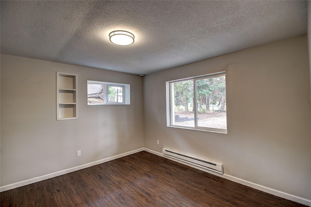 spare room featuring baseboard heating, dark wood finished floors, and baseboards