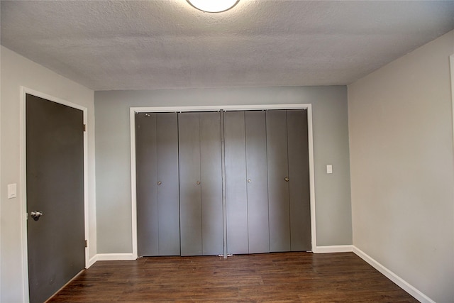 unfurnished bedroom featuring dark wood-style floors, a closet, and baseboards