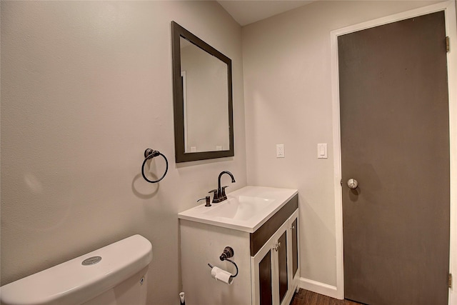 half bath featuring vanity, toilet, and baseboards