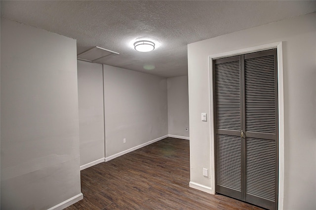 unfurnished bedroom with a textured ceiling, a closet, baseboards, and wood finished floors